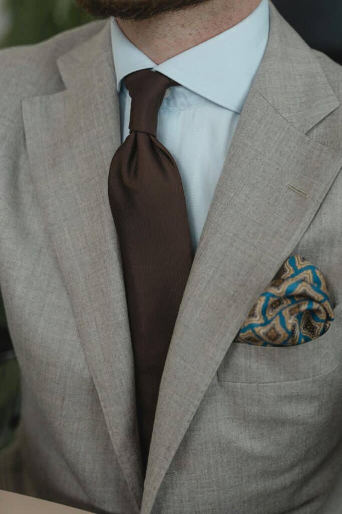 Homme avec une veste de costume grise et une cravate marron