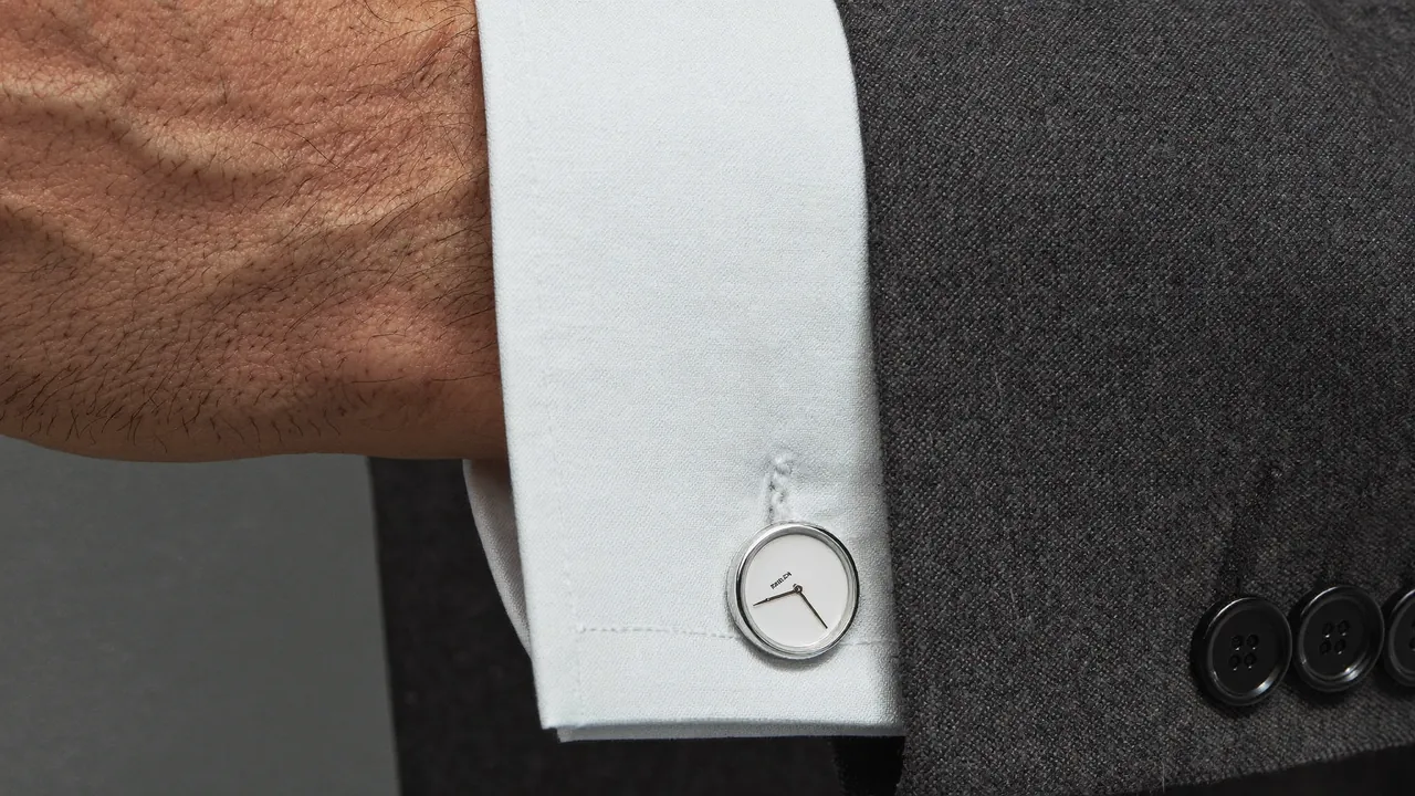 Poignet de chemise blanche avec bouton de manchette argent et nacre sous un costume