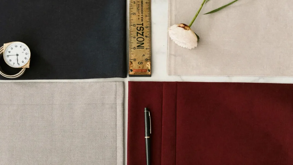 Échantillons de tissu costume de mariage marine, gris, beige et bordeaux sur marbre blanc