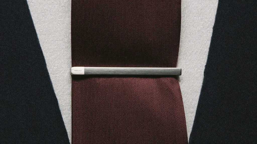 Pince à cravate argent sur cravate bordeaux soie et chemise blanche sous costume marine